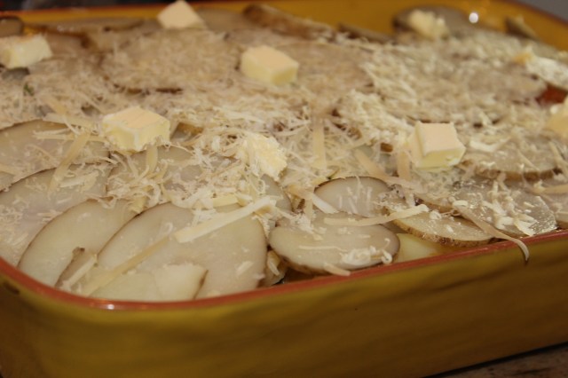 Top with sliced, partly boiled potatoes. Dot with butter and sprinkle your favorite melting cheese.